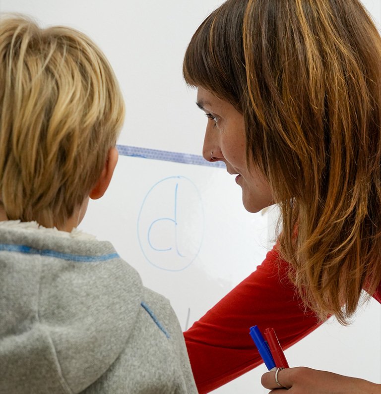 Pedagoga trabajando con un niño en la pizarra