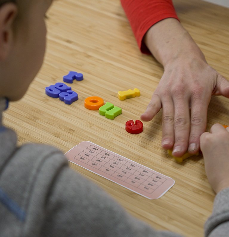 Manos de niño jugando con letras magnéticas de colores